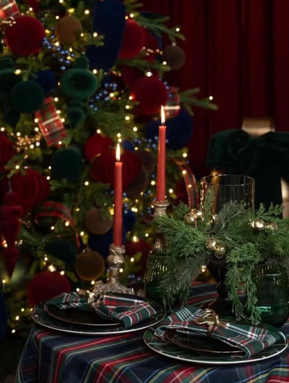 Decoração de sala clássica com paredes verdes e almofadas de tecido tartan encarnado, árvore de natal e festão sobre a lareira